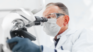 Image of a doctor looking at a kidney stone specimen under a microscope.